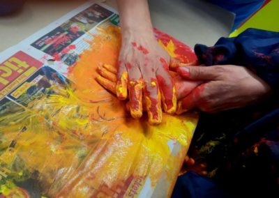 Kind nähert sich mittels Handführung an das Malen mit Händen an.